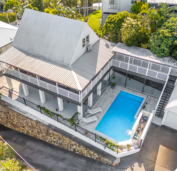 Aerial view of a modern house with a backyard pool and spacious deck area.